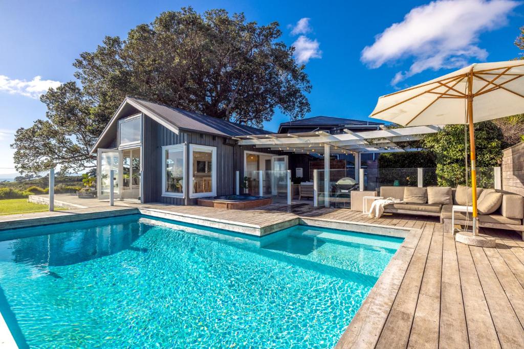 a house with a swimming pool and a patio at Palm Beach Retreat - Be My Guest Waiheke in Waiheke Island