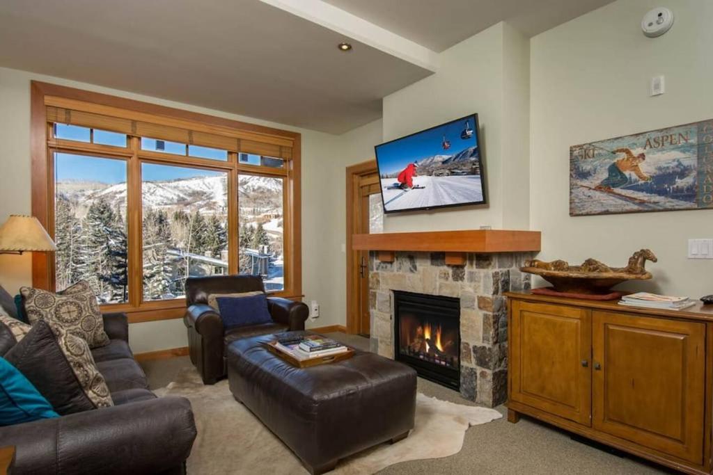 a living room with a fireplace and a tv at The Powder Den Cozy Alpine Basecamp in Snowmass Village