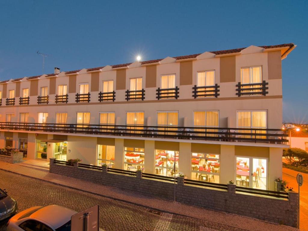 聖佩羅德姆的住宿－Hotel Miramar - São Pedro de Moel，一座大型建筑,晚上设有窗户和阳台