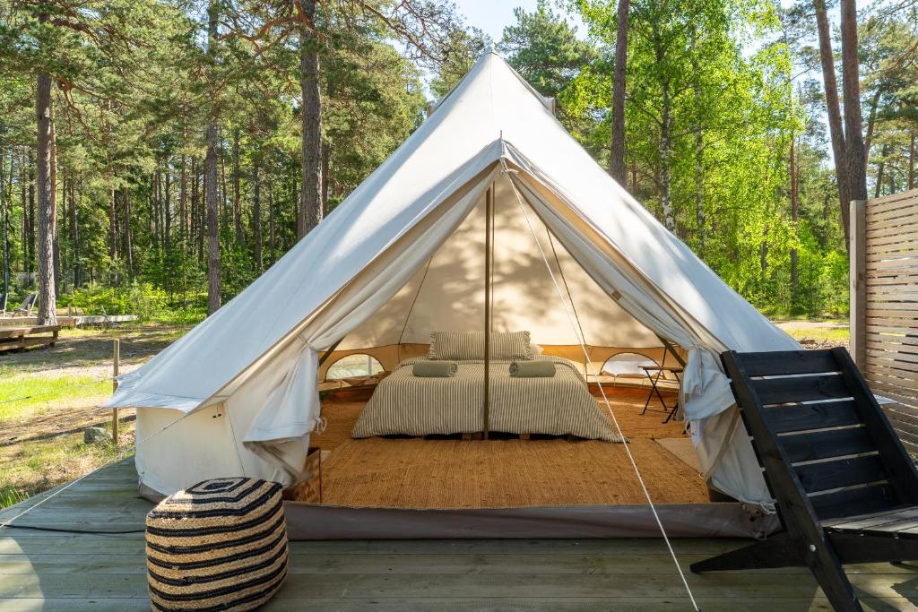 Tienda blanca con cama y silla en Glamping by the beach, en Hanko