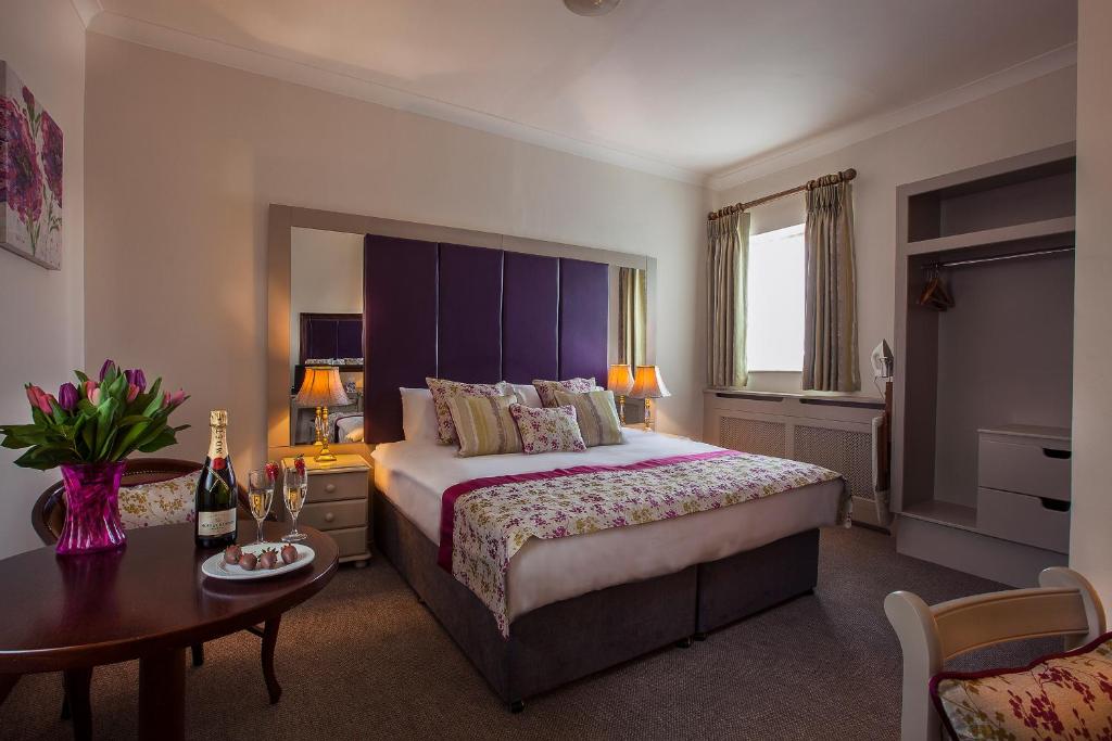 Breffni Arms Hotel في Arvagh: غرفة فندقية بسرير كبير وطاولة