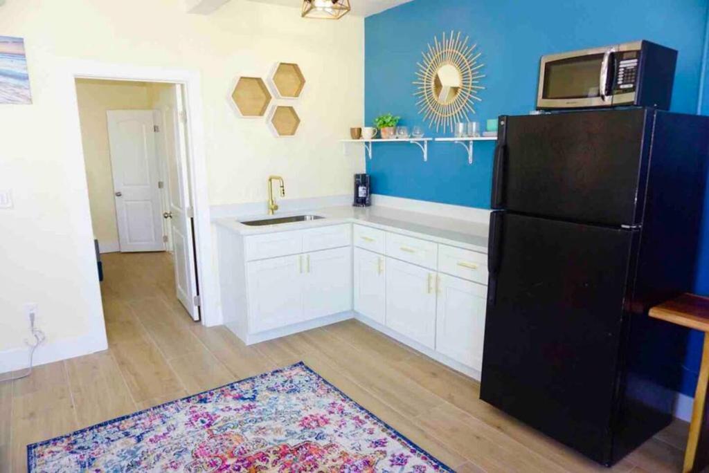 a kitchen with a black refrigerator and a blue wall at Pets Ok Steps 2 Ocean Center Walk 2 Beach in Daytona Beach