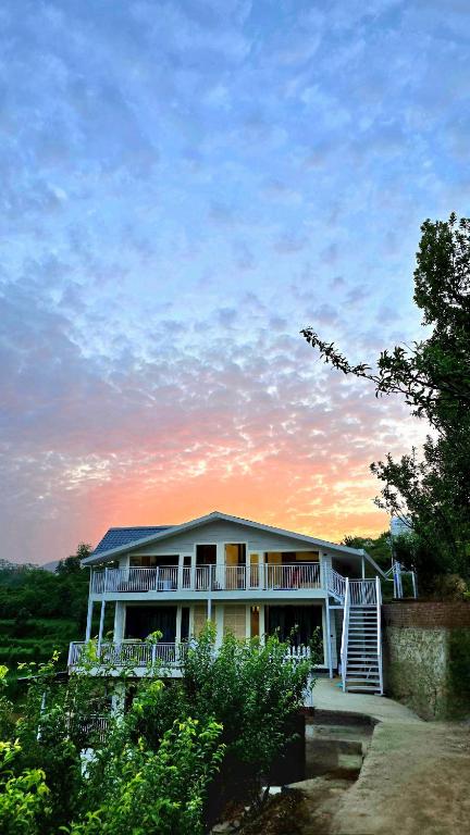 a large house with a sunset in the background at Rosewood Cottage in Mukteshwar