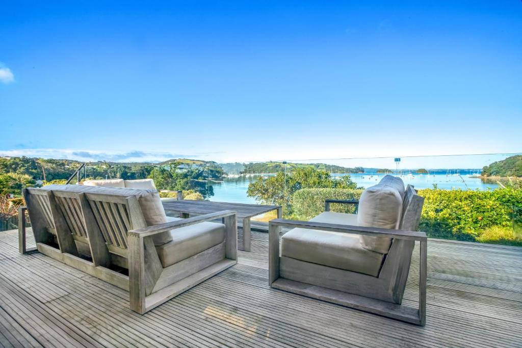 two chairs on a deck with a view of the water at Shelley Beach Homestead in Waiheke Island