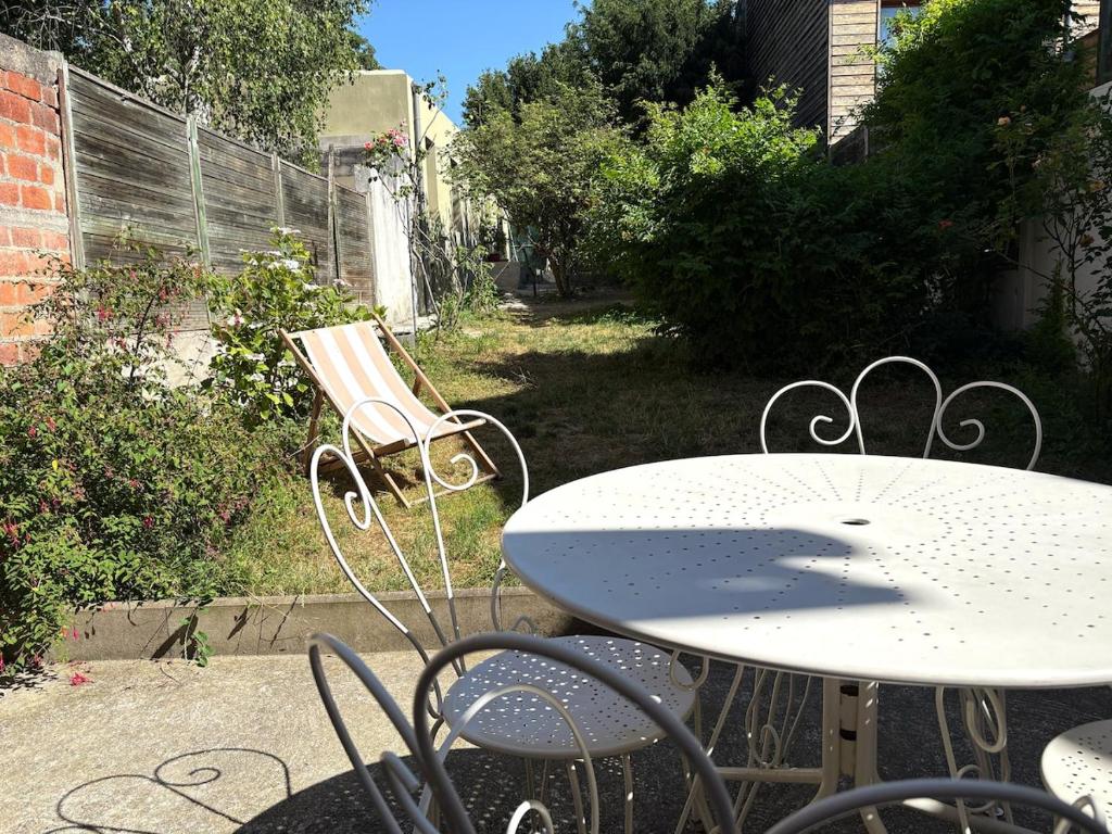 a table and chairs with a table and a bench at Maison charmante - 10 min de Paris in Montreuil