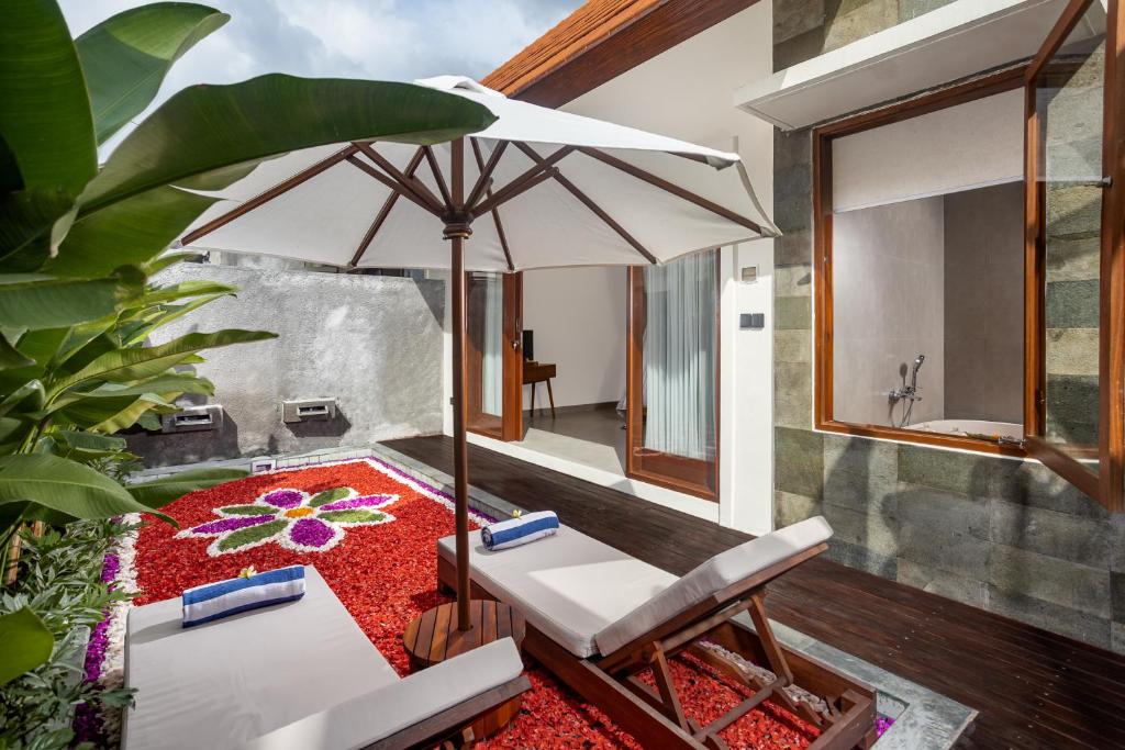 a patio with an umbrella and a table and chairs at Jenna Villa by GenuineHost in Ubud
