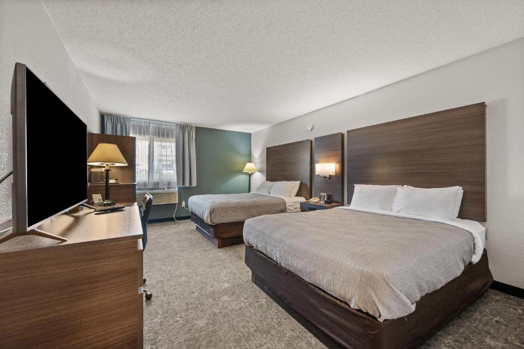 a hotel room with two beds and a flat screen tv at Quality Inn Spearfish I-90 in Spearfish