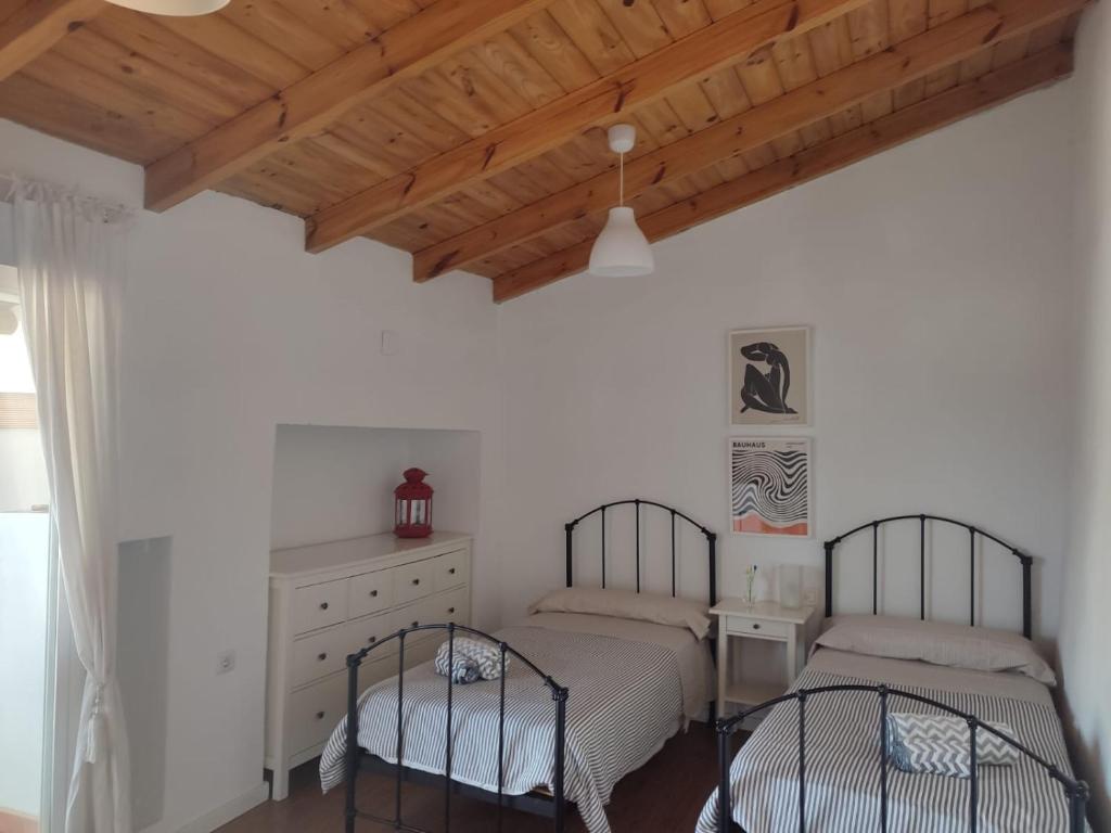 a bedroom with two beds and a wooden ceiling at Casa del Valle Encantado in Galaroza