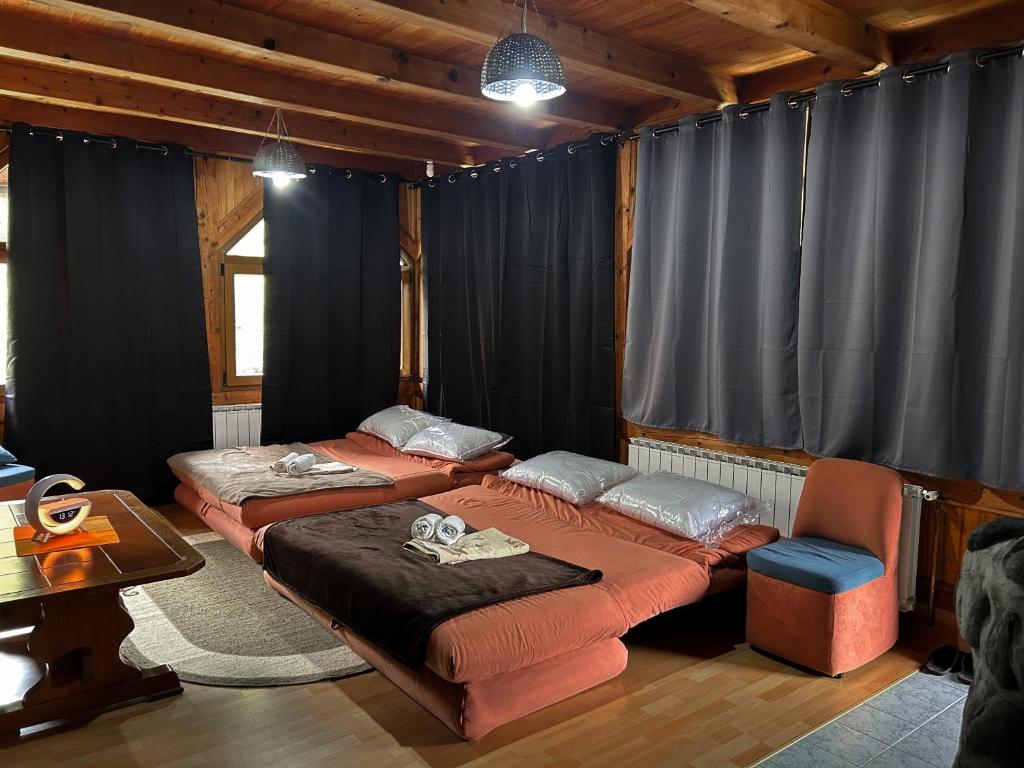 two beds in a room with black curtains at Krivaja River Retreat - Jacuzzi, Pool and Basketball 