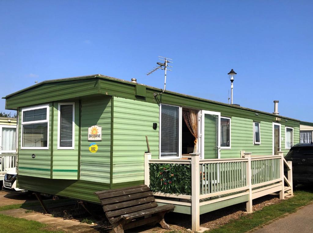 a green house with a bench in front of it at PD Wonderwall Caravan, Direct beach access & Beds made on arrival & GCH in Ingoldmells