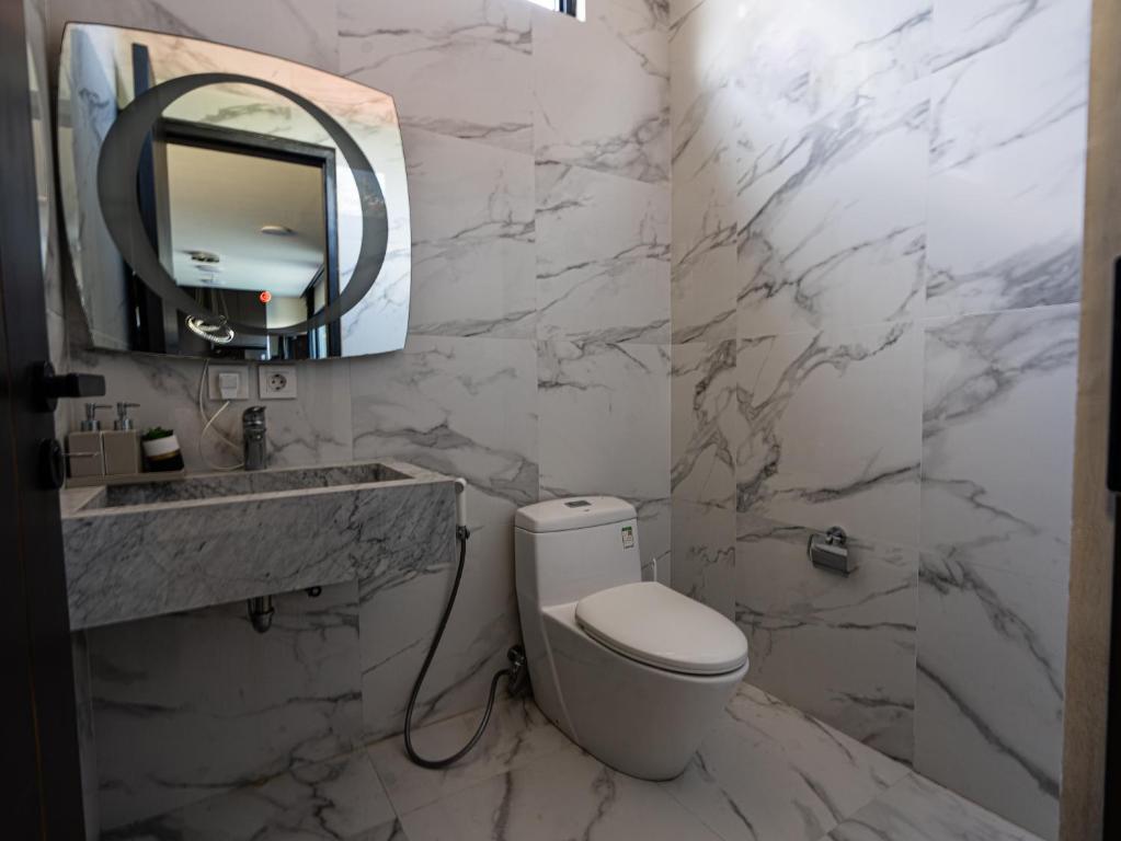 Un baño blanco con inodoro y espejo. en Villa Maya, en Kerobokan