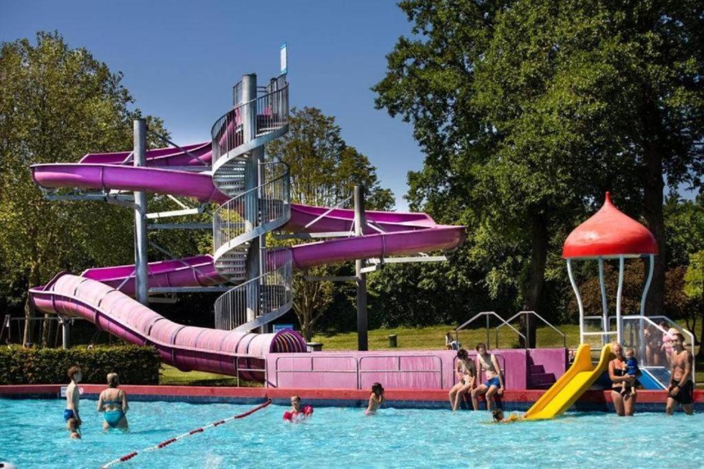a group of people in a pool with a water slide at Casa del Carmen airco, privé hottub en sauna, WiFi and 2 bedrooms in Heinkensand