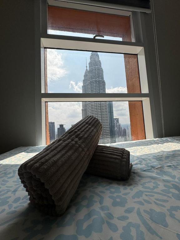 a bed with a large window with a view of a building at Nest In The Sky in Kuala Lumpur