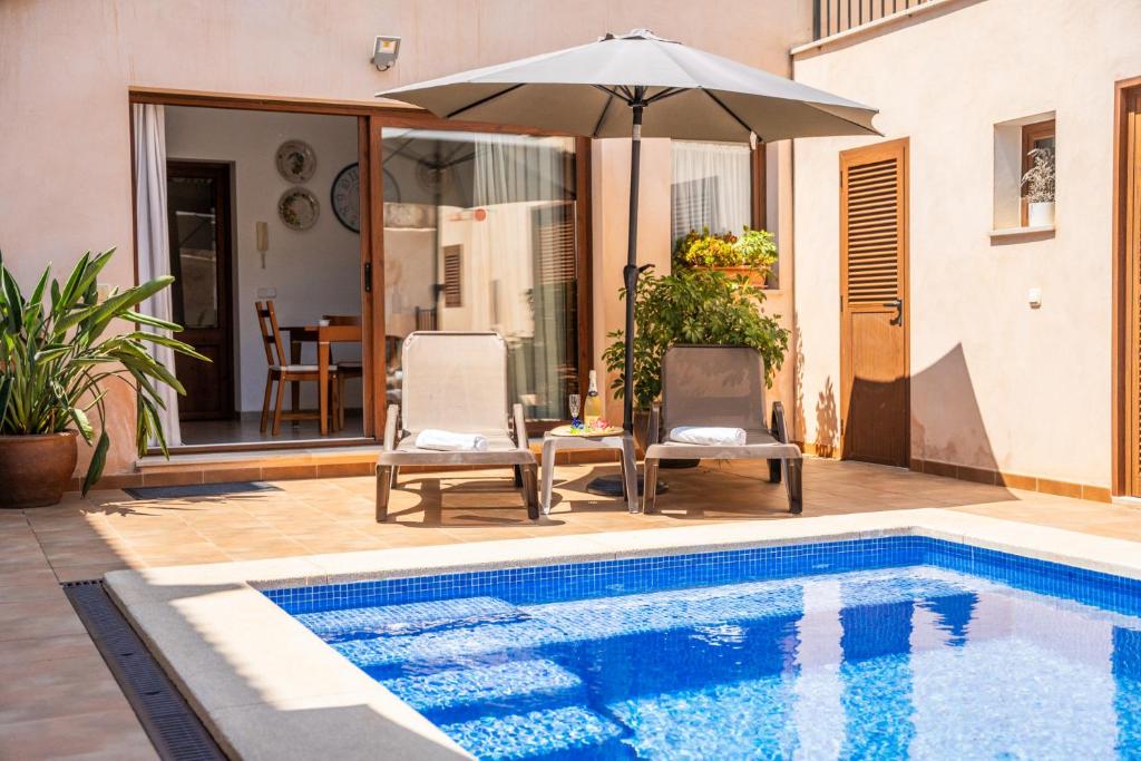 a swimming pool with two chairs and an umbrella at Ideal Property Mallorca - Villa Placeta in Sa Pobla