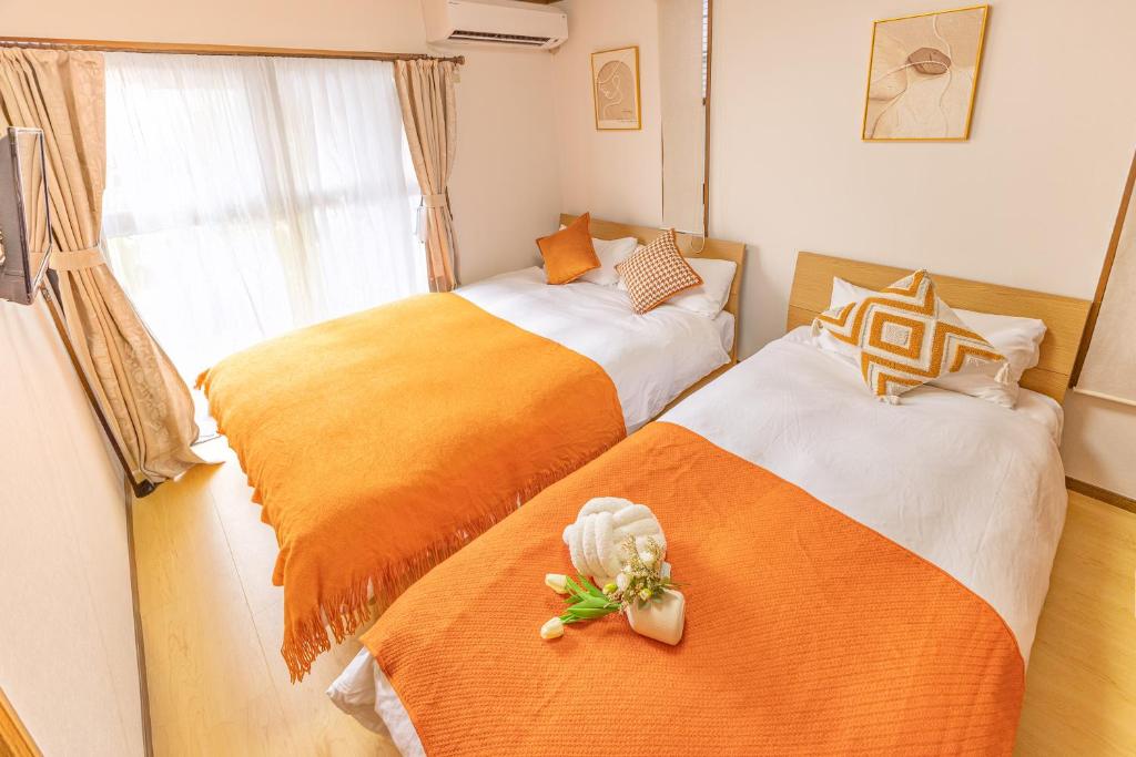a bedroom with two beds with orange and white sheets at tokyo in Wada