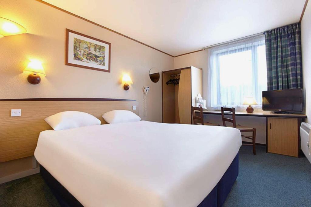 a hotel room with a large white bed and a desk at The Beacon Hotel, Cardiff, Part of the AG Collection in Cardiff