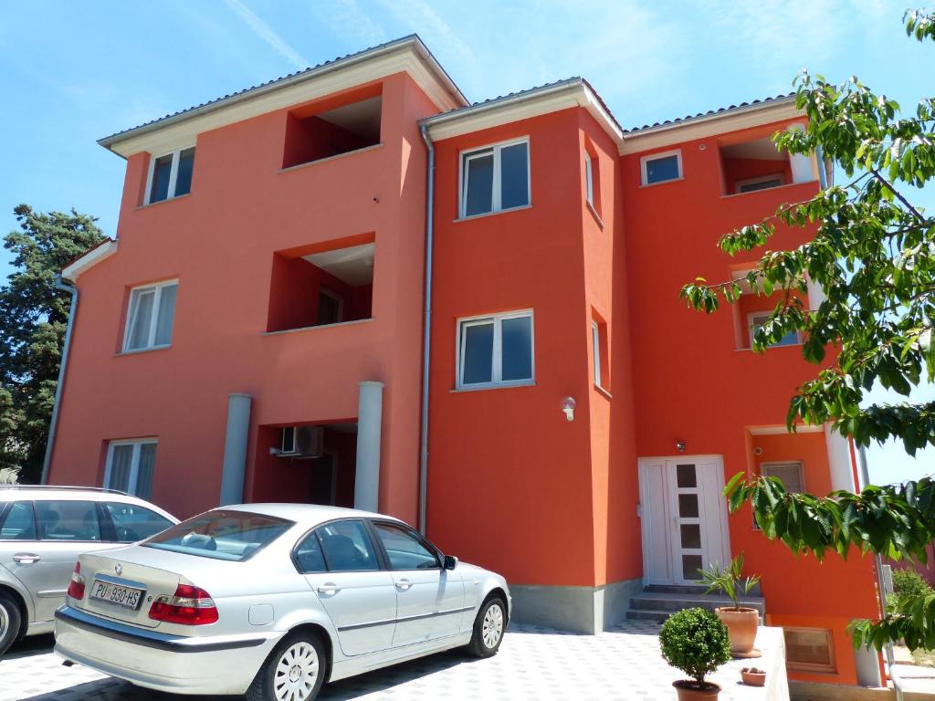 a red building with a car parked in front of it at Apartment Luzia in Banjole