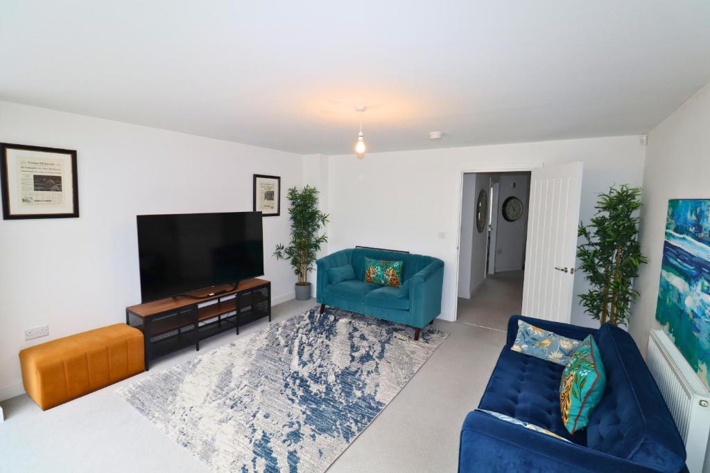 a living room with two blue chairs and a flat screen tv at High Wycombe Stunning Stylish Four Bedroom House in High Wycombe