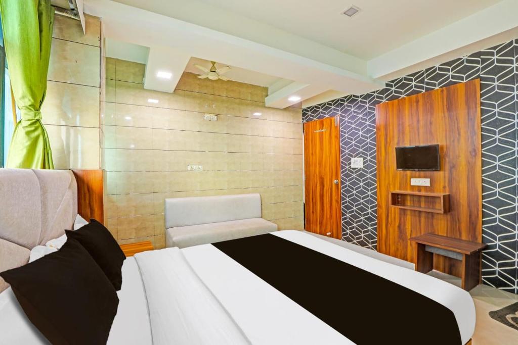 a bedroom with a bed and a chair and a television at Hotel RK in Ahmedabad