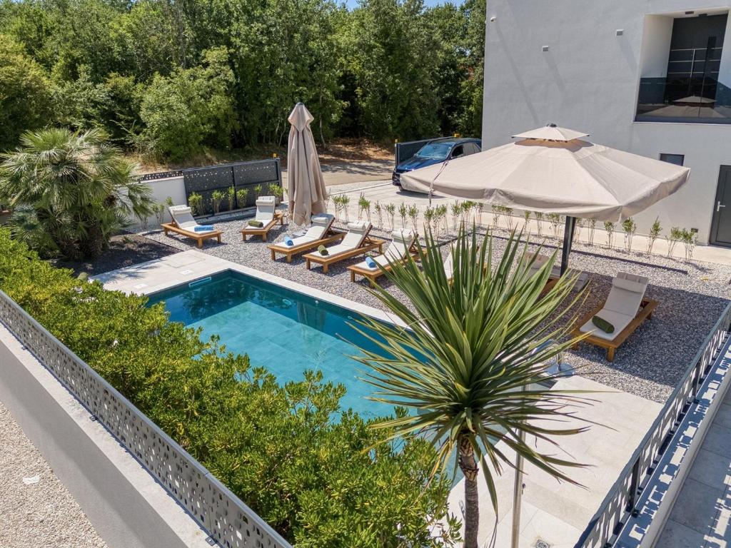 ein Swimmingpool mit Sonnenschirm und Liegestühlen und ein Swimmingpool in der Unterkunft Villa Elisadora in Poreč