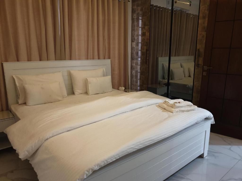 a bedroom with a large white bed with a mirror at The Luxe Nook in Islamabad