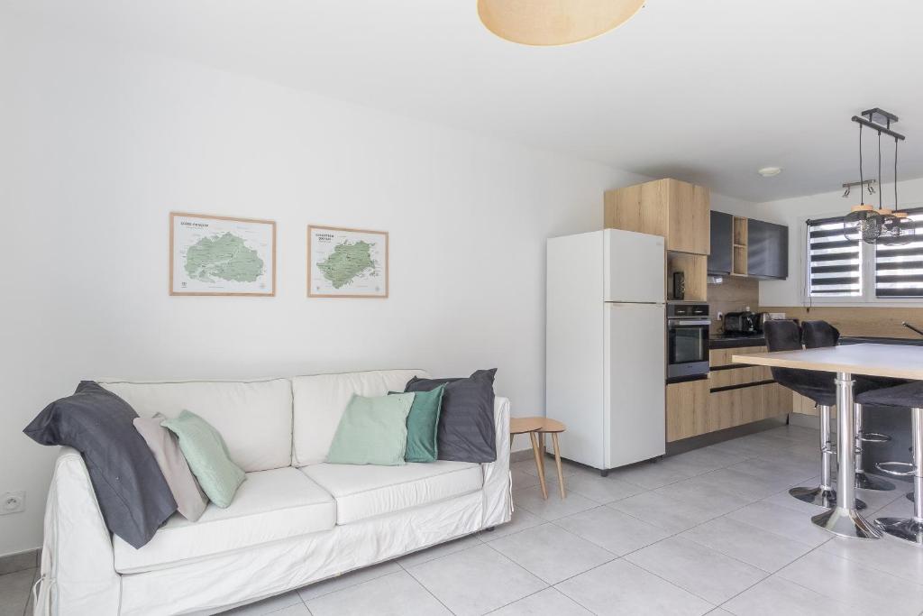 a living room with a white couch and a kitchen at Morgon Garden Lodge - Proche de la Rivière in Savines