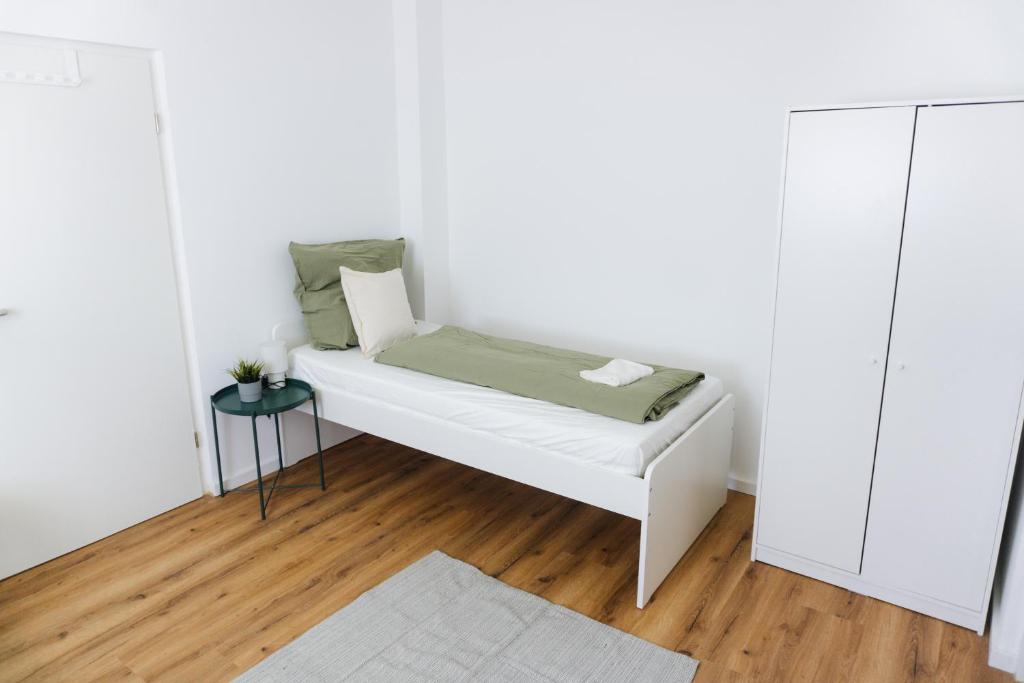 a white bed in a room with a wooden floor at Ferienwohnung Zur Wieskapelle W3 - ideal für Monteure in Straubing