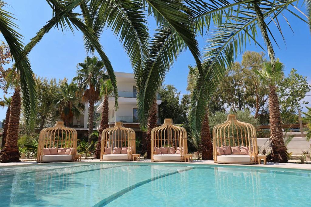 a swimming pool with four chairs and palm trees at NŪSA suites & villas in Pefkohori