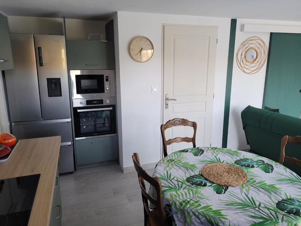a kitchen with a table and a dining room with a clock at Chez Louise in Arboussols