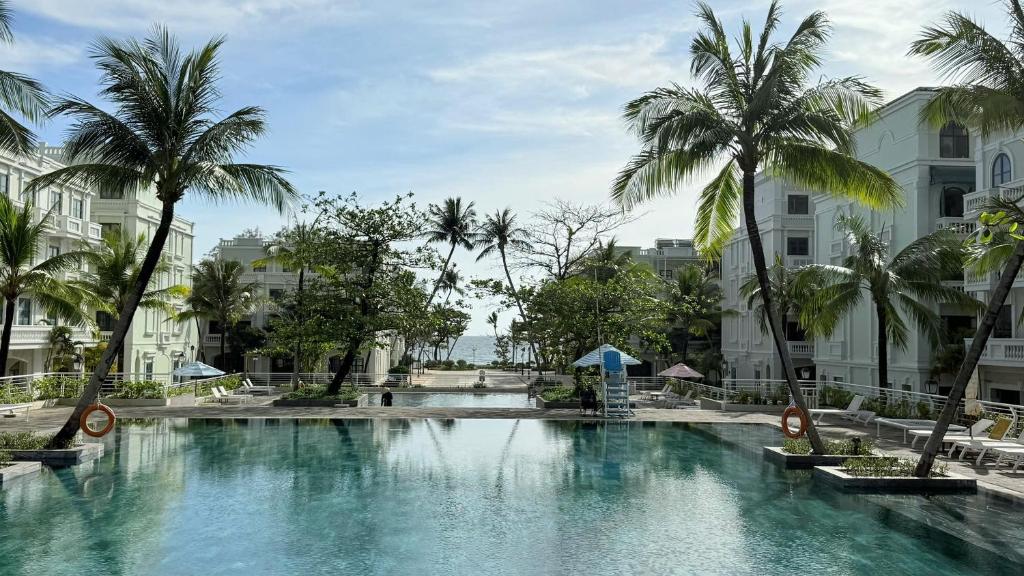 a large swimming pool with palm trees and buildings at Sunset Marina Hotel in Phu Quoc