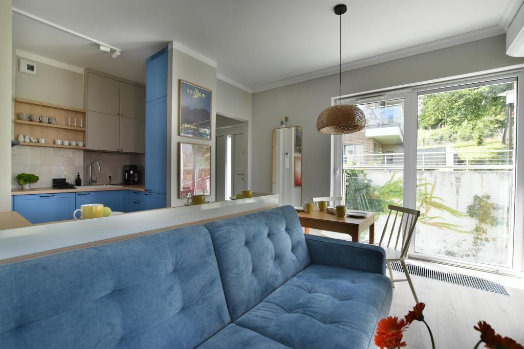 un canapé bleu dans un salon avec une cuisine dans l'établissement BeeMeeMuu - Magiczny Horyzont Wisła, à Wisła