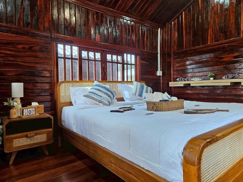 a bedroom with a large bed with wooden walls at I-Lay House Koh Kood in Ko Kood