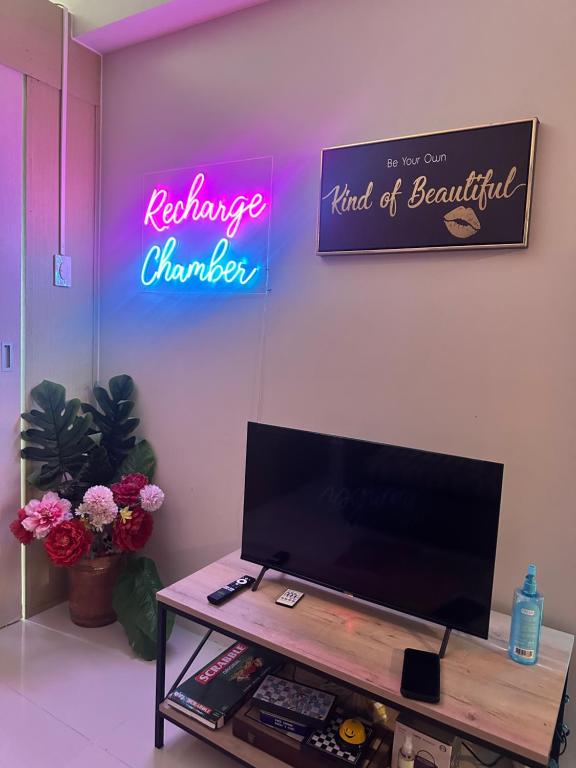a living room with a television and a neon sign at Simoy Recharge Chamber in Kaybagal