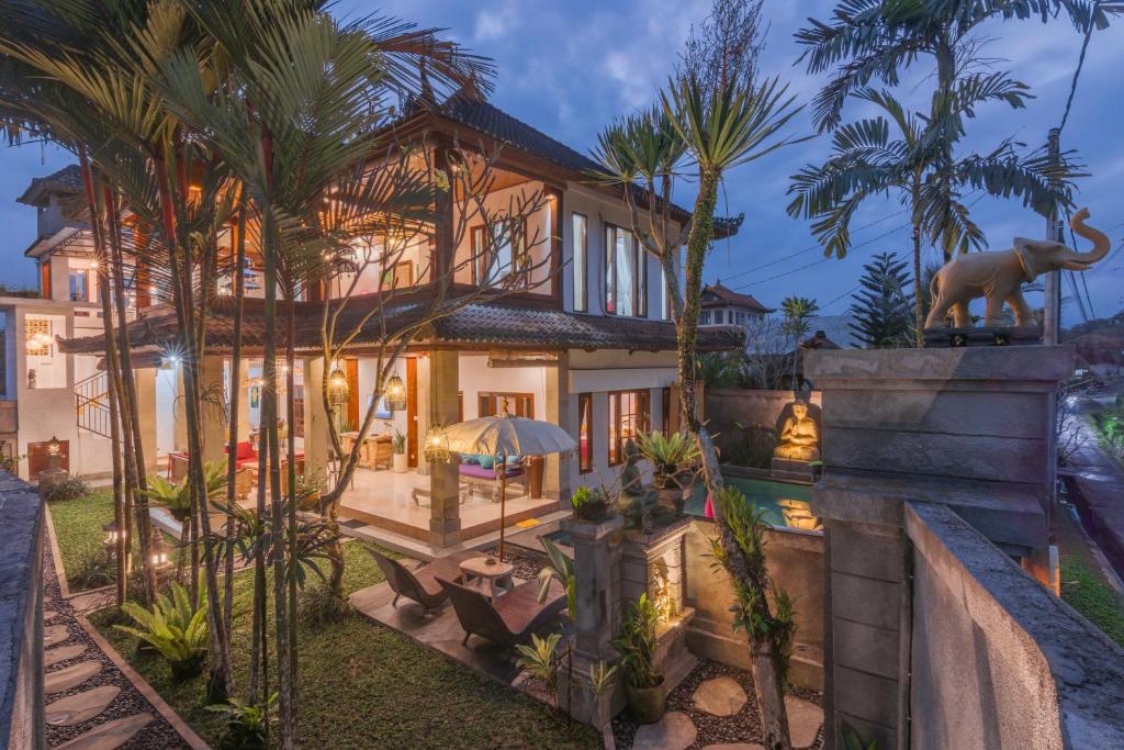 een exterieur van een huis met palmbomen bij Villa Mangku in Ricefield in Ubud
