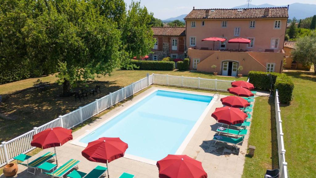 a swimming pool with umbrellas and chairs and a house at Villa al Falchetto by VacaVilla in Capannori