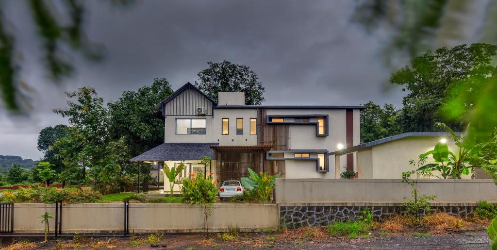 a house with a car parked in front of it at SaffronStays Fernshade - 3BR Khopoli retreat, patio, lawn picnics & riverside walks, quick Mumbai access via Atal Setu in Jambhulpāda