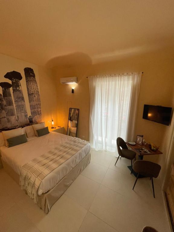 a bedroom with a large bed and a desk with a table at Bìfara Rooms in Palermo
