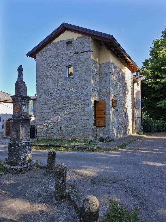 an old stone building with a clock in front of it at La Coccola del Borgo in Fanano