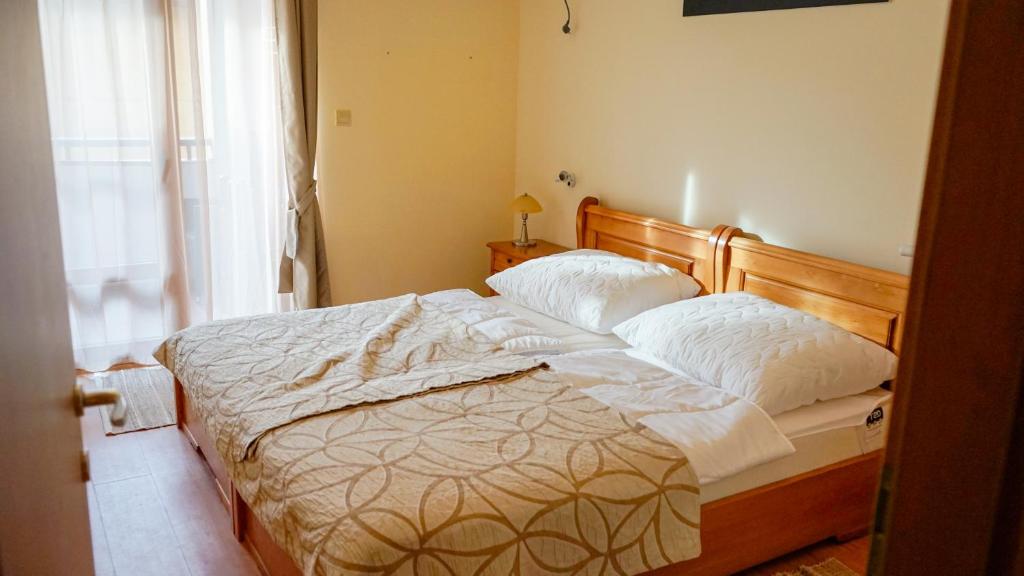 a bedroom with a bed with white sheets and a window at Apartmány Bulharsko Sveti Vlas - Garden of Eden in Sveti Vlas