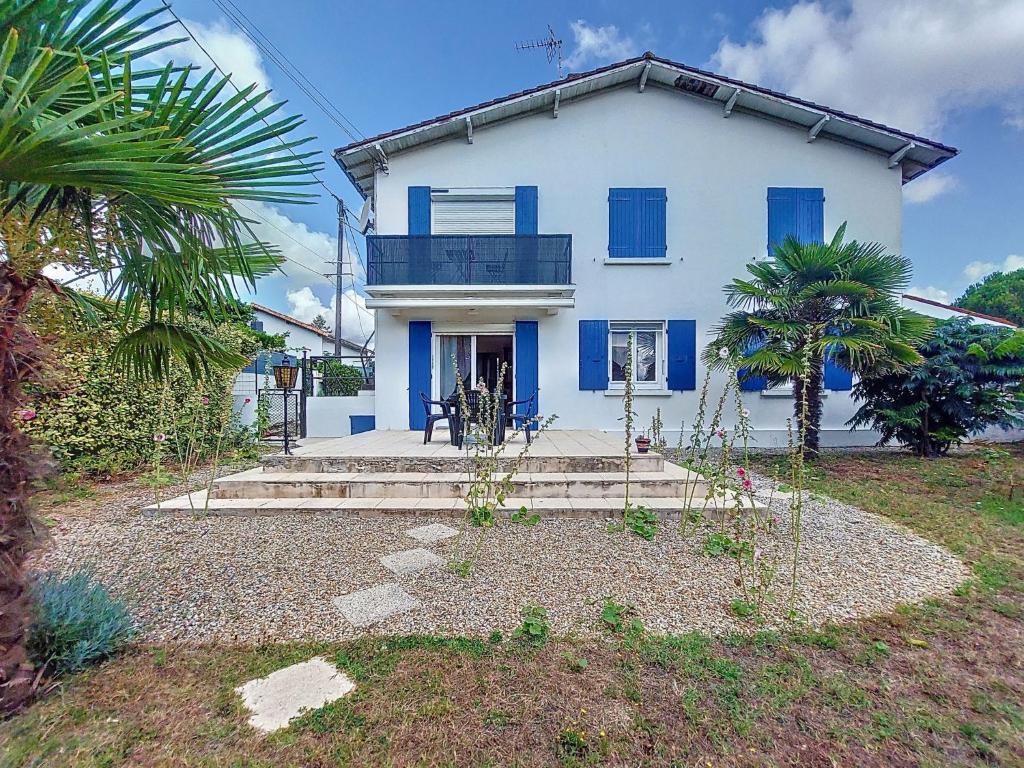 a white house with blue shutters and a palm tree at Apartment L'Océan by Interhome in Vaux-sur-Mer
