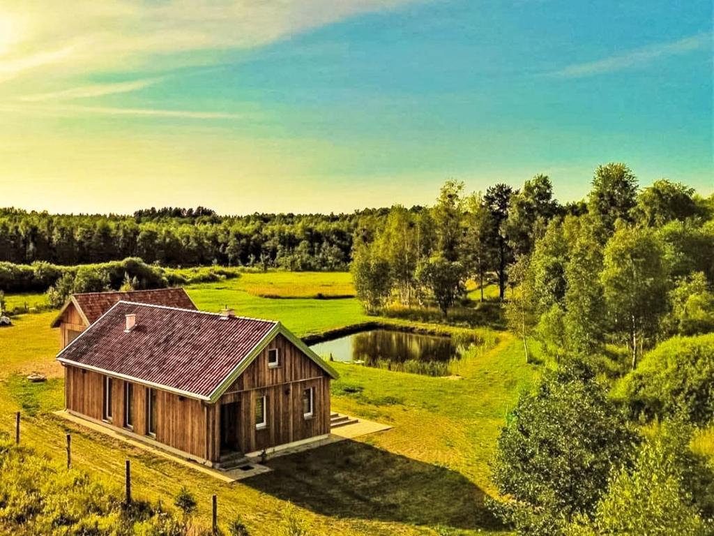 una piccola casa di legno in un campo con uno stagno di Holiday Home Zagroda nad Krutynią by Interhome a Spychowo