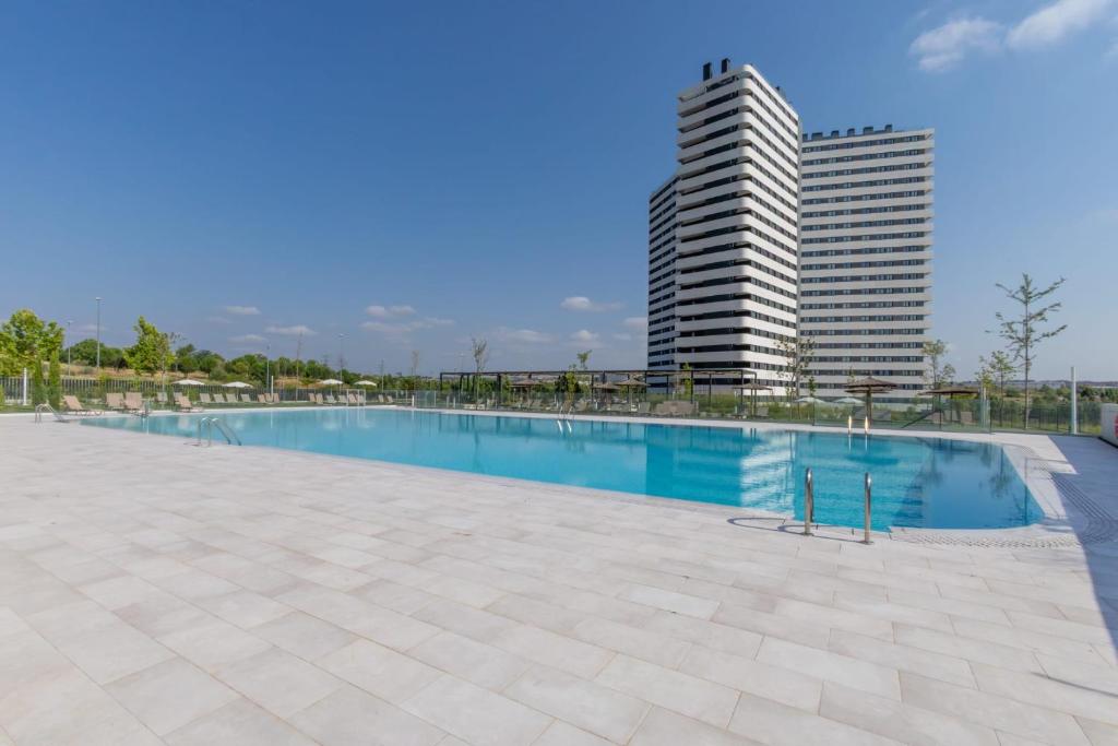 a swimming pool with a tall building in the background at Be Casa Alcobendas in Alcobendas