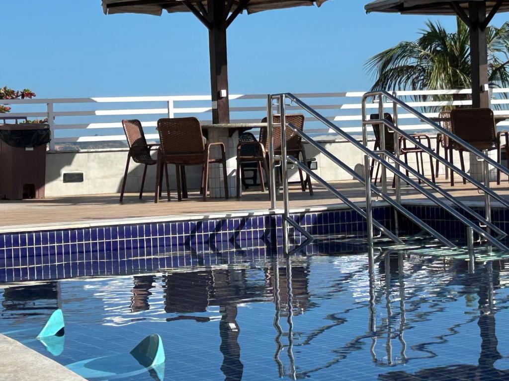 uma piscina com cadeiras e uma mesa e um pouco de água em Pipa's Bay Apartamento - Sea View em Pipa