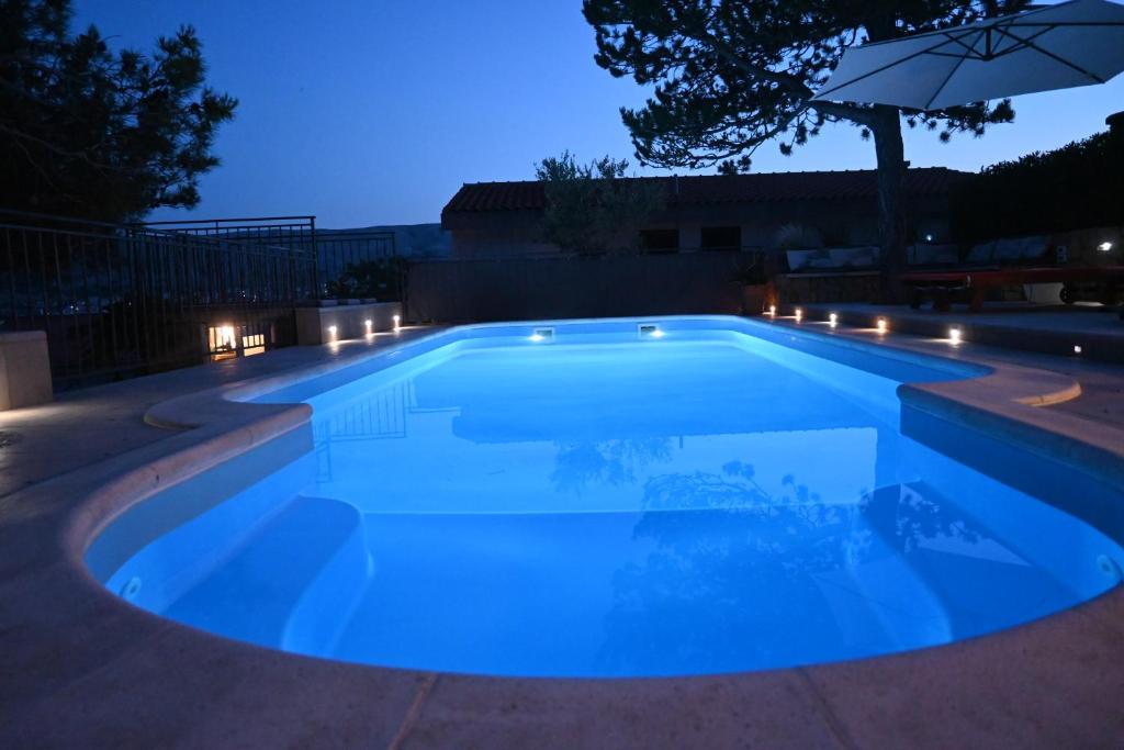 a swimming pool lit up at night with an umbrella at Apartments Tea Pag in Pag