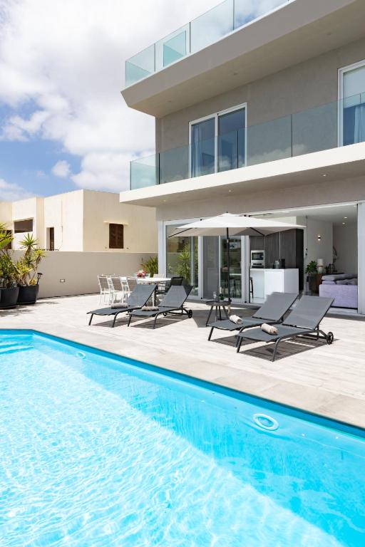 a swimming pool in front of a house at Villa Ixoria Unit 1 with Private Pool by ArcoCollection in St. Julianʼs