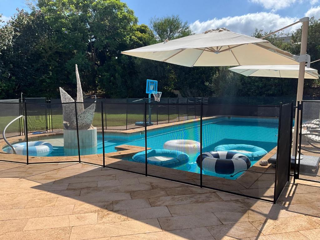 a swimming pool with an umbrella and two chairs and a basketball hoop at Sunny Coastal villa, luxury gateway! in Caesarea