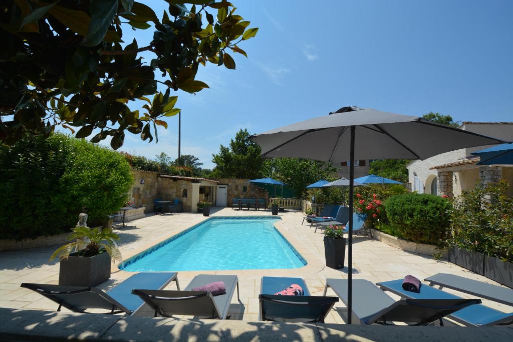 a swimming pool with lounge chairs and an umbrella at Les villas du Golf Mougins in Mougins