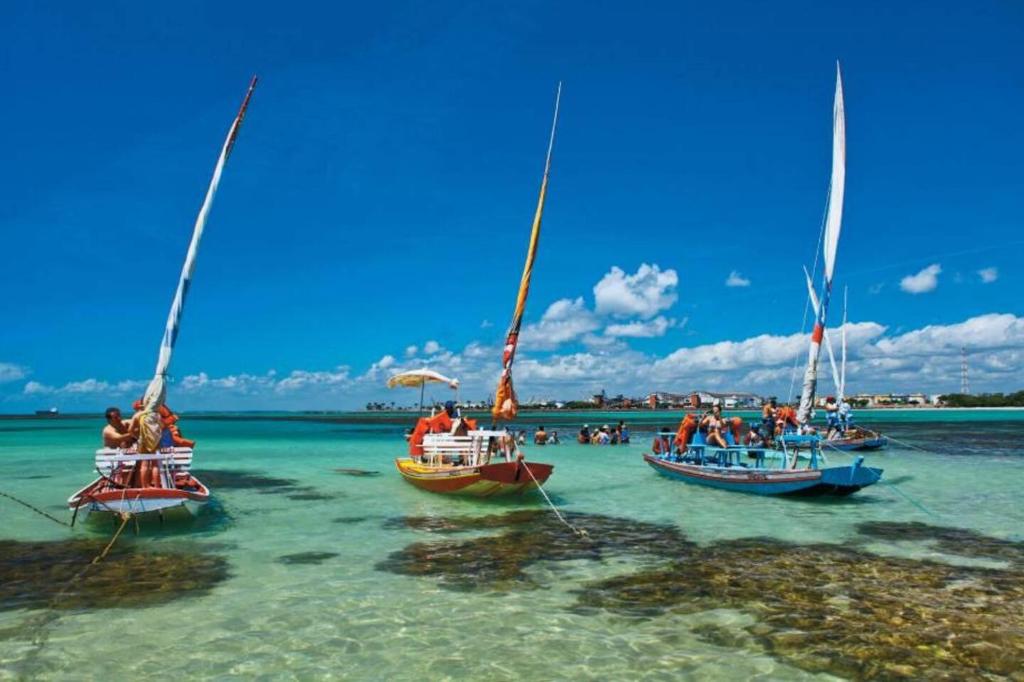 three boats in the water on a beach at Suíte in Maceió