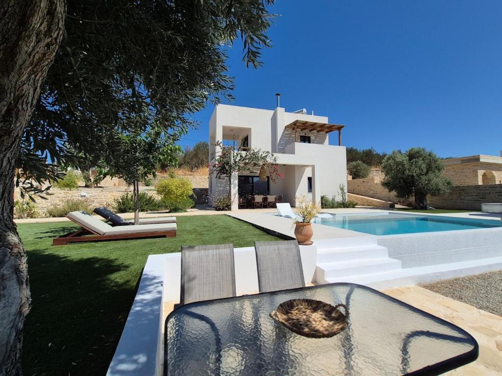 a villa with a pool and a table and chairs at Villa Neroli Pool & Mountain Views in Pitsidia in Pitsidia