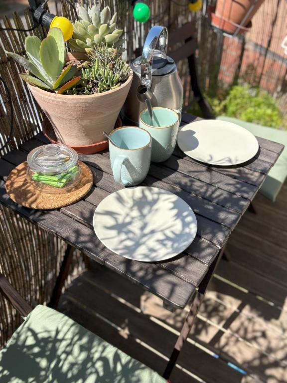 a wooden table with plates and a plant on it at Le Jean Moulin Vert in Sète